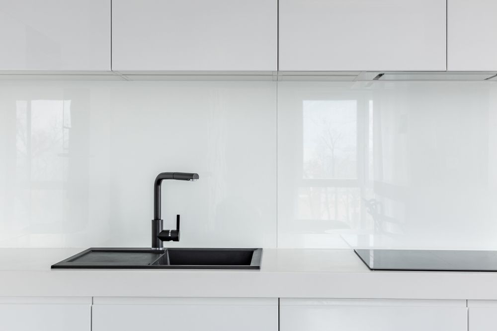 A Kitchen With White Cabinets, A Black Sink, And A Black Stove Top Oven — Citrus Clean Central Coast In Lake Haven, NSW