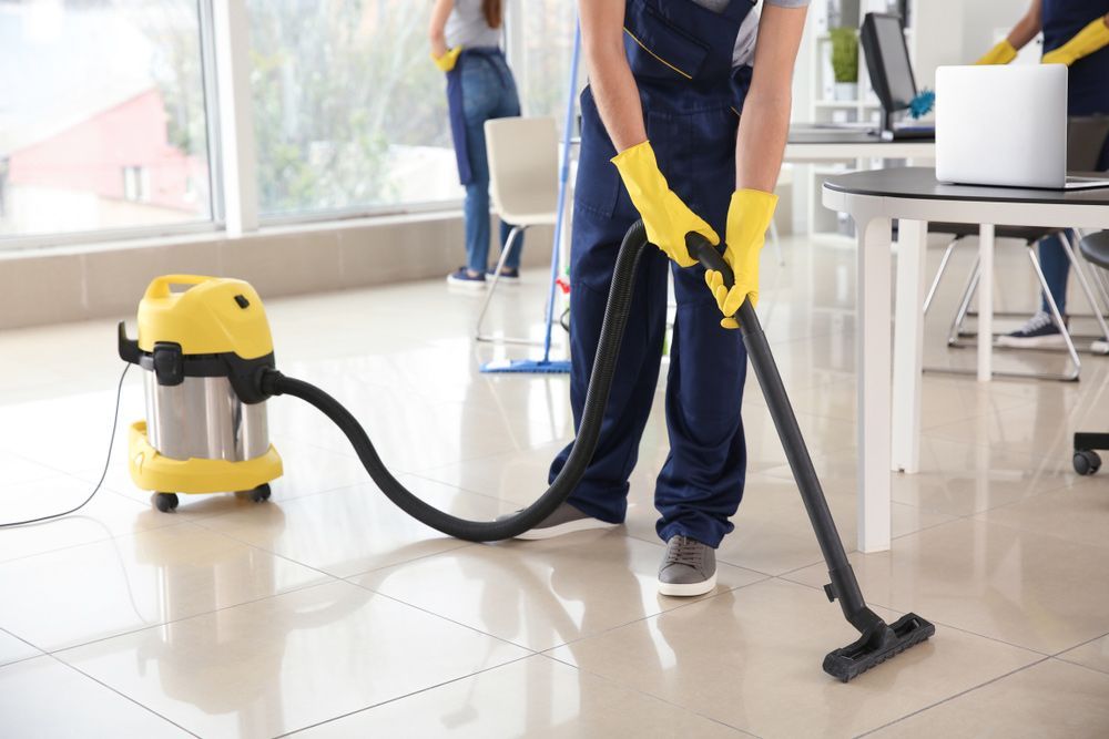 Person in Yellow Gloves Vacuums Office Floor Two Others in Background — Citrus Clean Central Coast In Lake Haven, NSW
