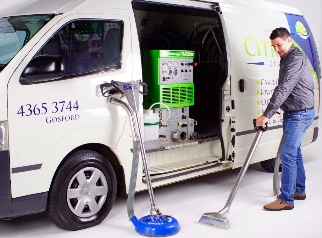 A Man Is Cleaning A Van With A Vacuum Cleaner — Citrus Clean Central Coast In Lake Haven, NSW