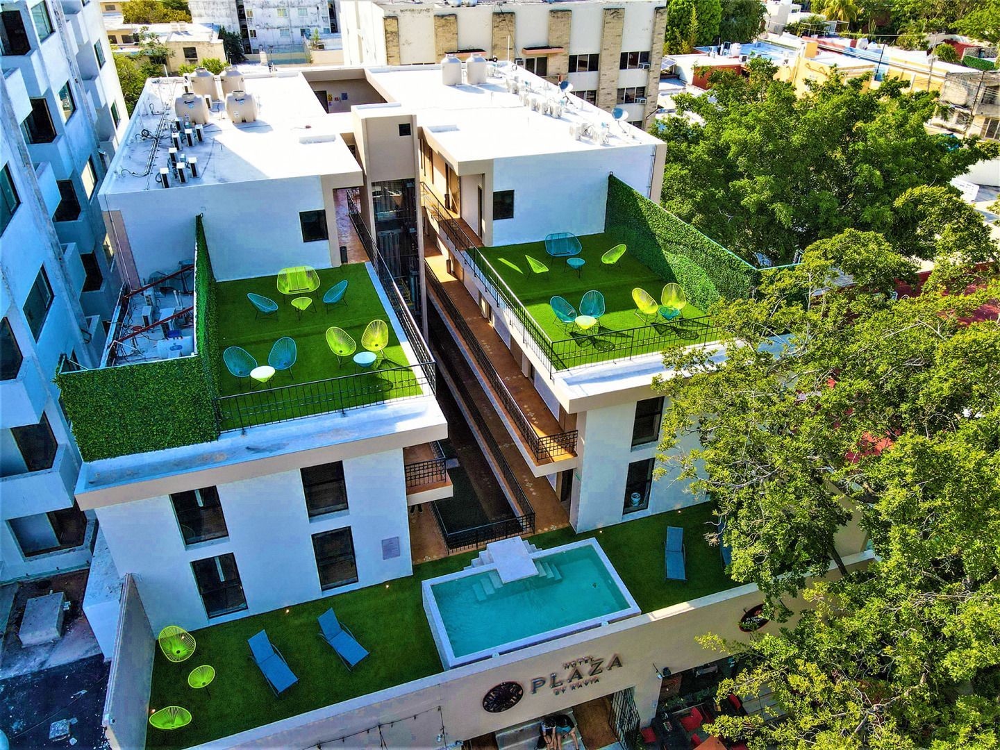 Vista aérea del Hotel The Plaza con piscina en la azotea y zonas verdes para sentarse.