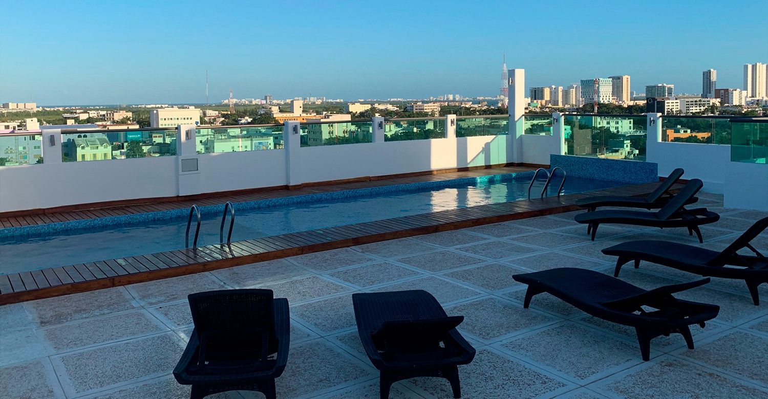 Piscina en la azotea con tumbonas con vistas al horizonte de la ciudad en un día soleado.