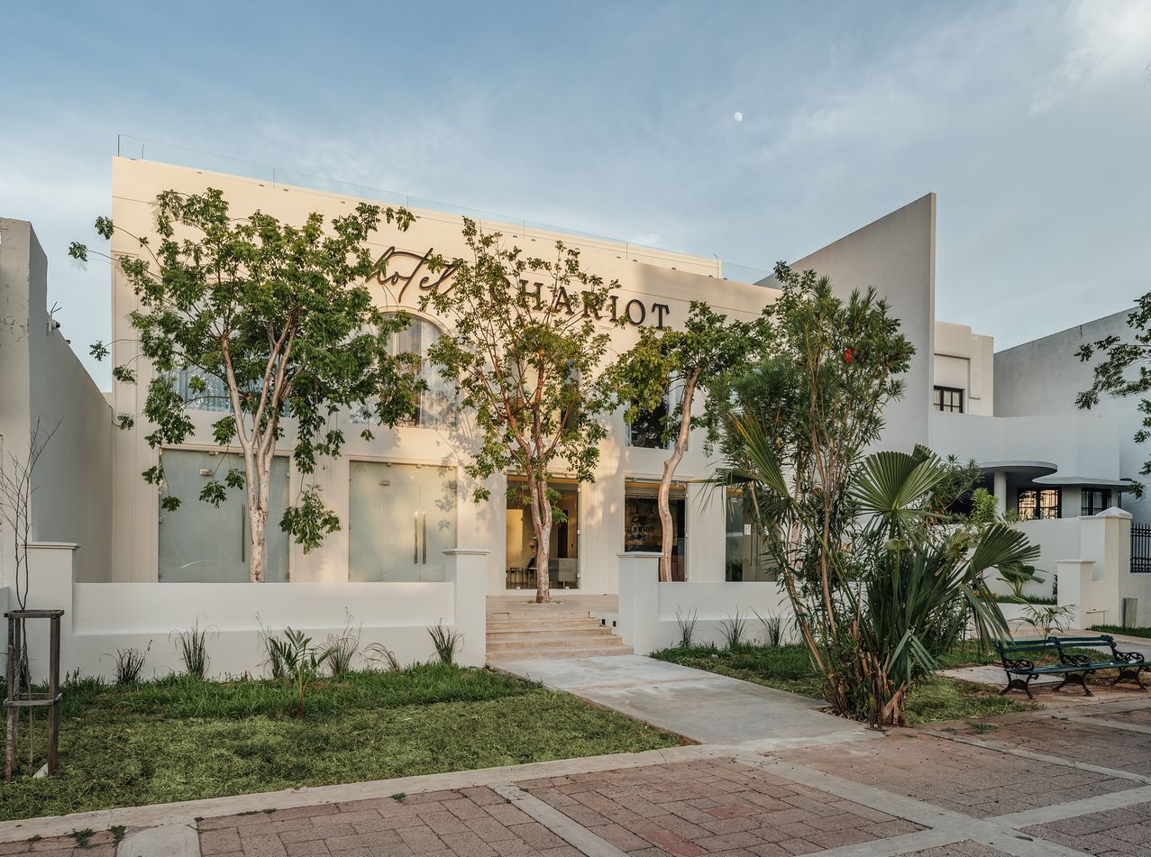 Edificio blanco con cartel de "Comportamiento"; árboles al frente.