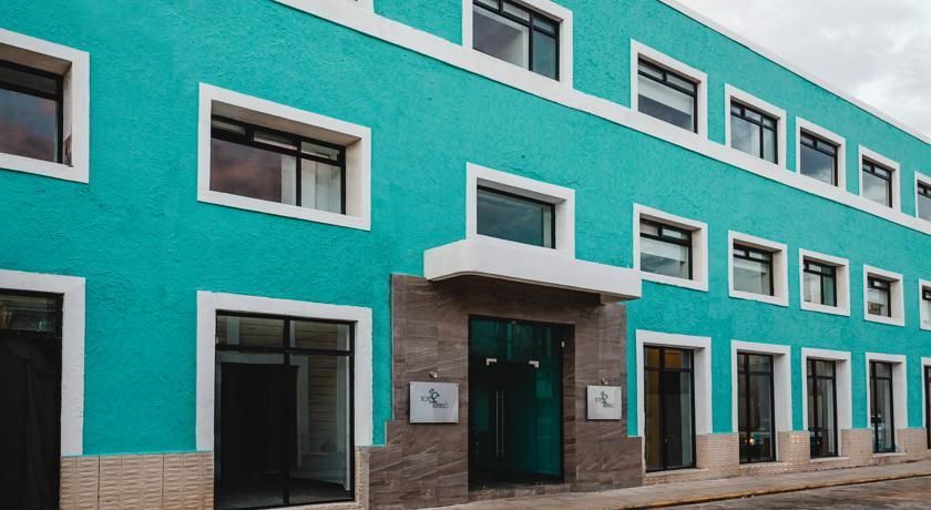 Edificio turquesa con molduras blancas, múltiples ventanas y una entrada de piedra marrón.