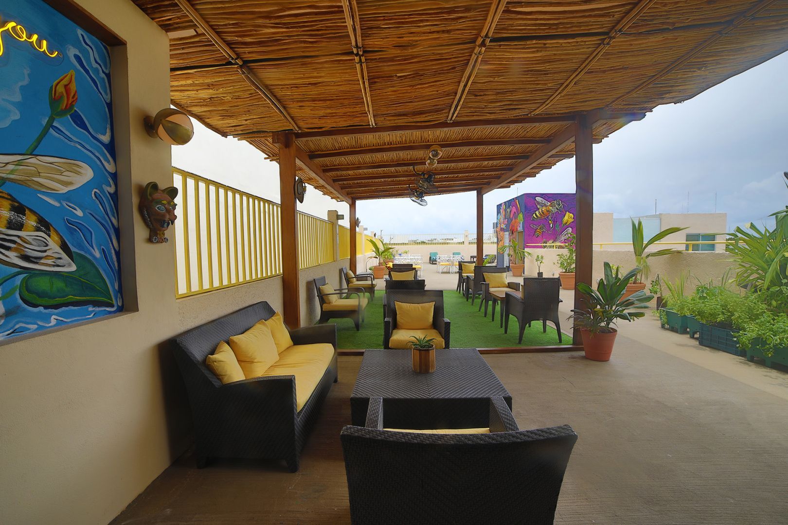 Patio en la azotea con asientos bajo un dosel de juncos y vistas a la playa.