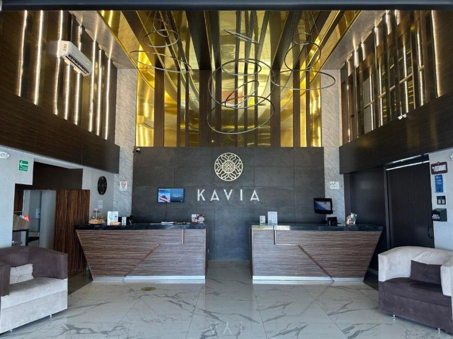 Lobby del hotel con mostradores de recepción, logotipo de Kavila y detalles dorados en el techo.