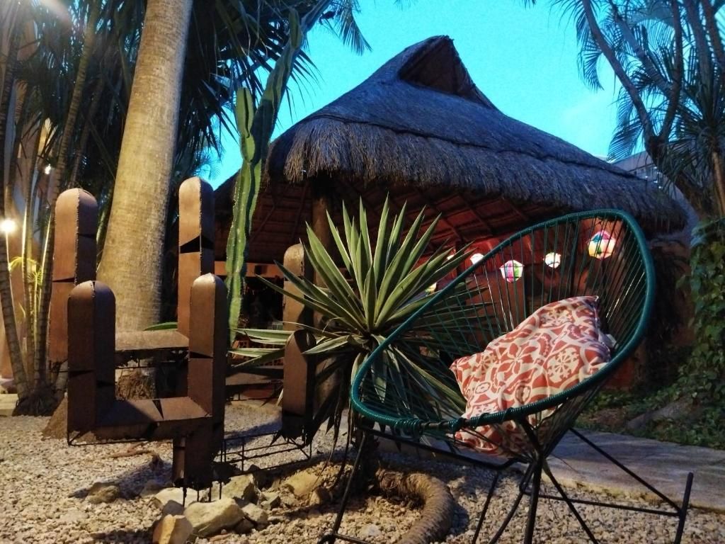 Área de estar al aire libre de temática tropical con una cabaña con techo de paja, una escultura de cactus.