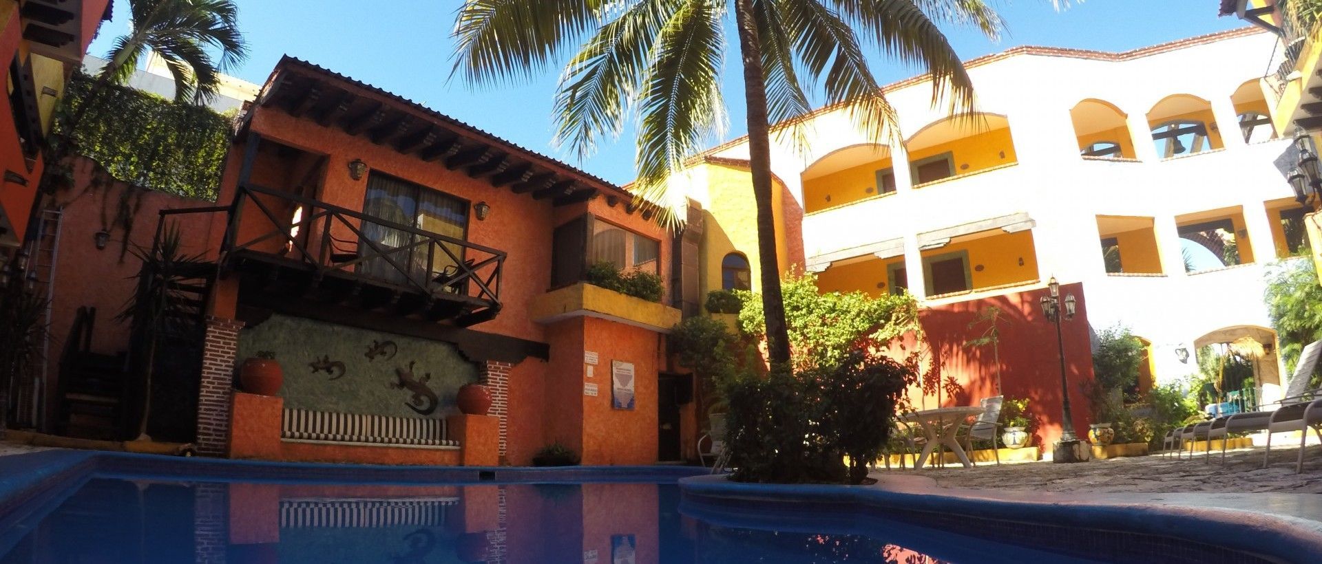 Edificios con balcones y piscina en un entorno tropical.
