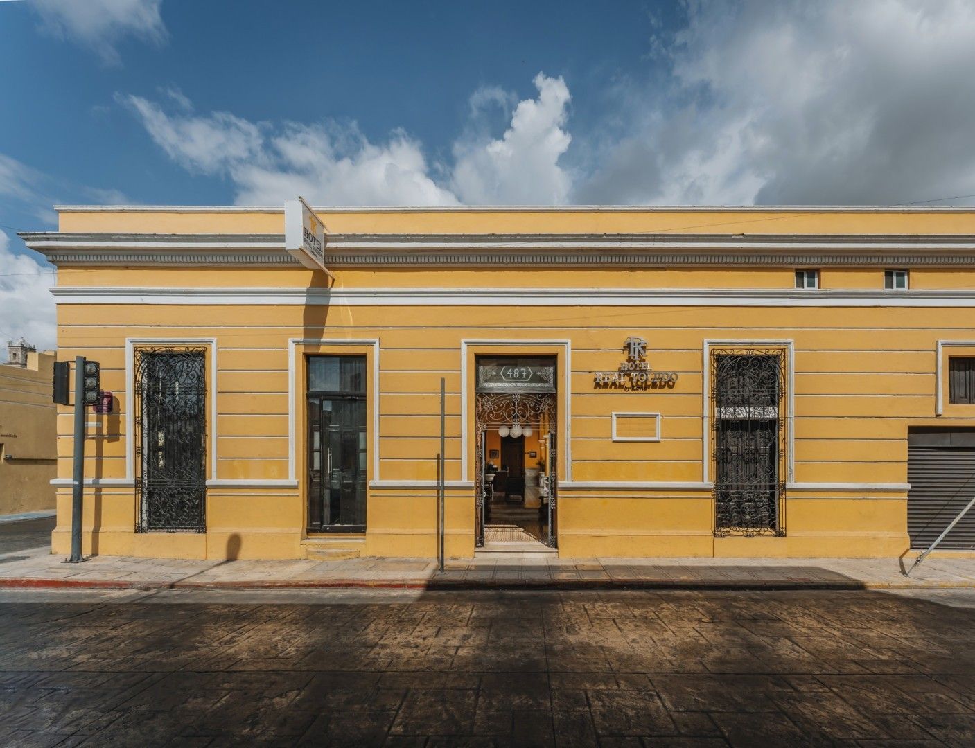 Edificio amarillo con detalles de hierro forjado negro y un cartel sobre la puerta.