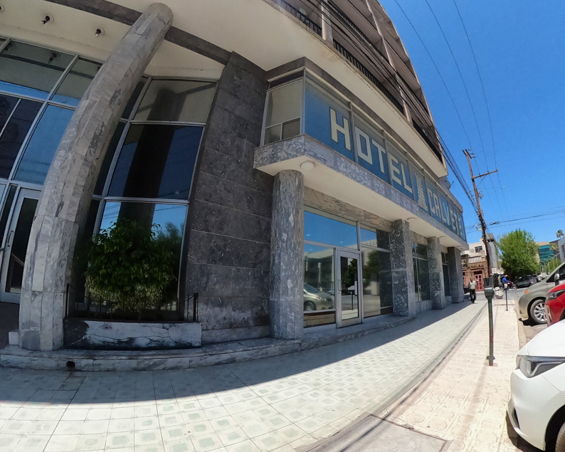 Fachada del hotel: piedra gris y exterior de cristal. Letrero "Hotel Royal" sobre la entrada.
