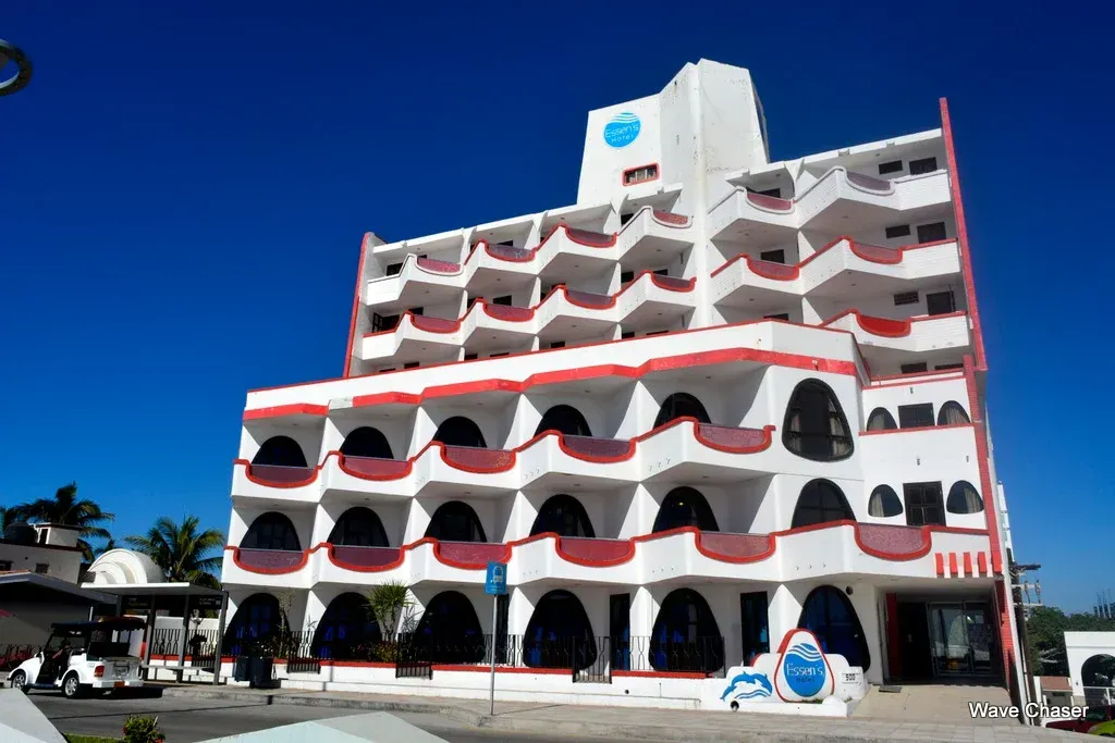 Edificio blanco y rojo de varios pisos con ventanas arqueadas contra un cielo azul.