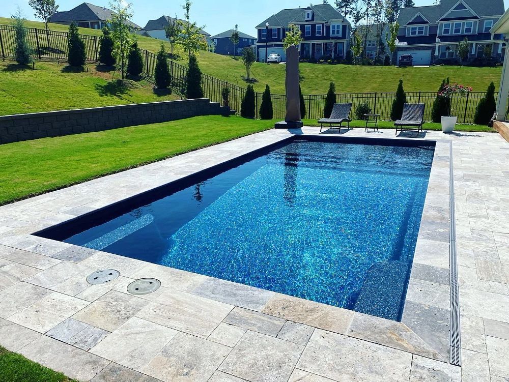Pool with brick patio, white fence, and beach house in the background.
