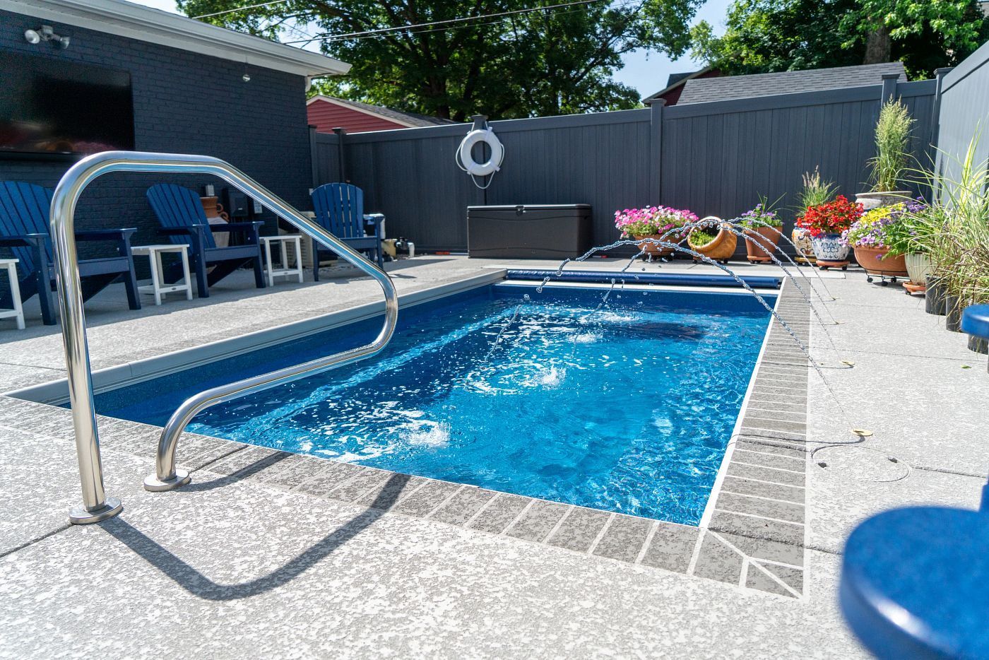 Small blue pool with bubbling water, surrounded by concrete and blue accents. A handrail is on the left.