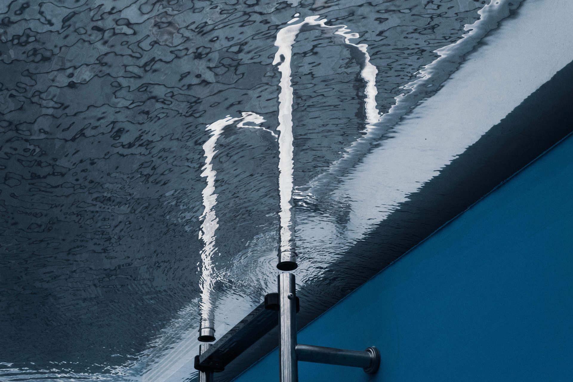Silver ladder against a blue wall and textured ceiling; water droplets.