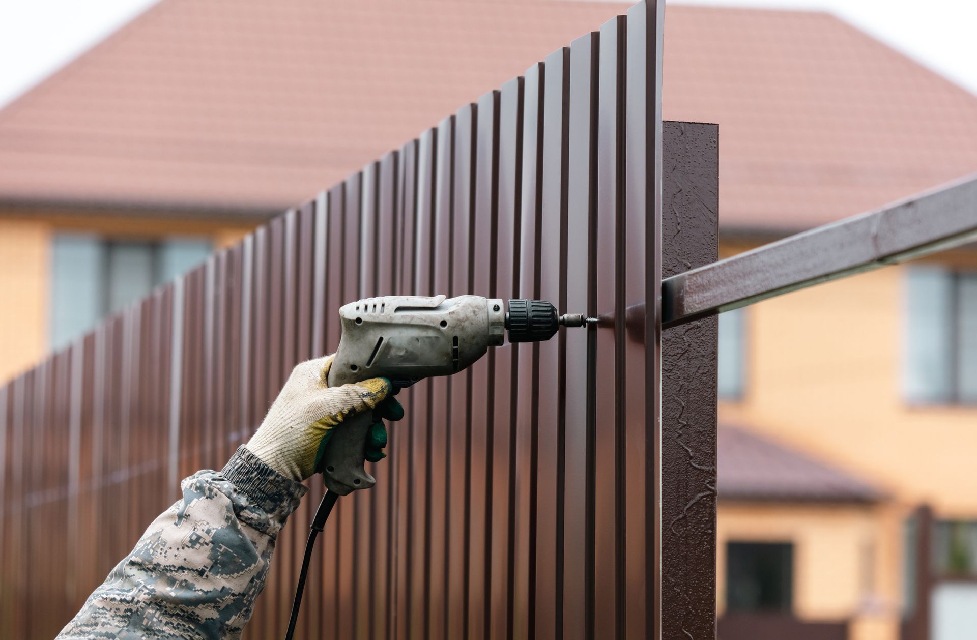 Workers install a metal profile fence.