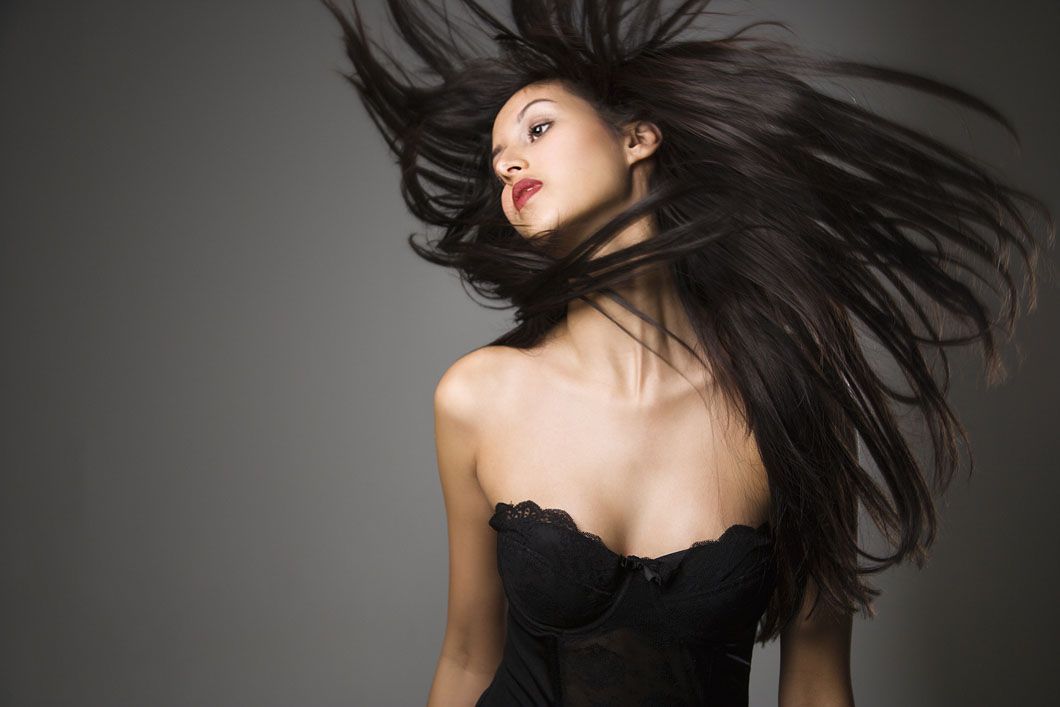 A woman in a black dress with her hair blowing in the wind.