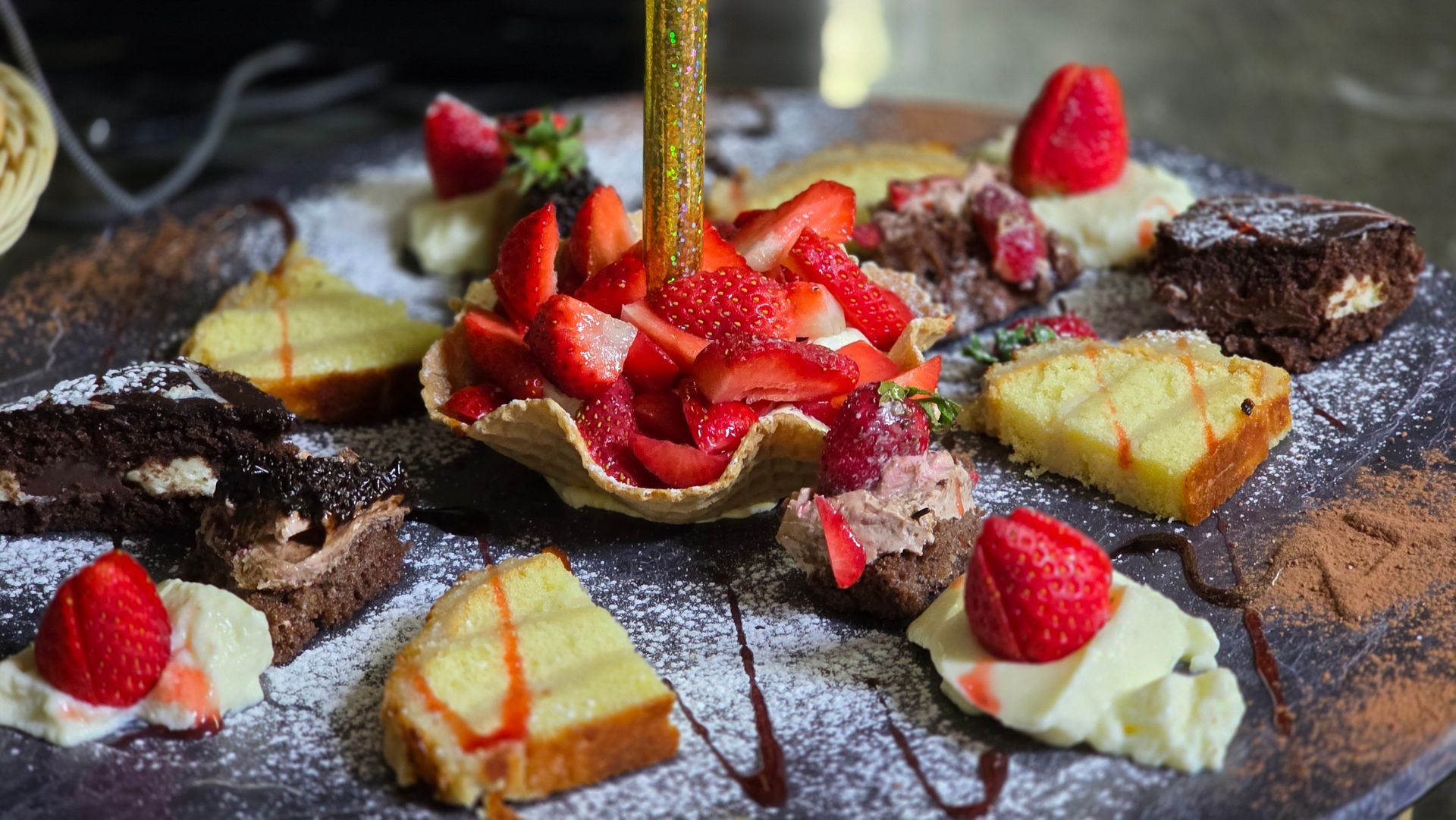 Un vassoio di dessert con fragole a fette, brownie al cioccolato, torta gialla e ciuffi di panna spolverata di zucchero.