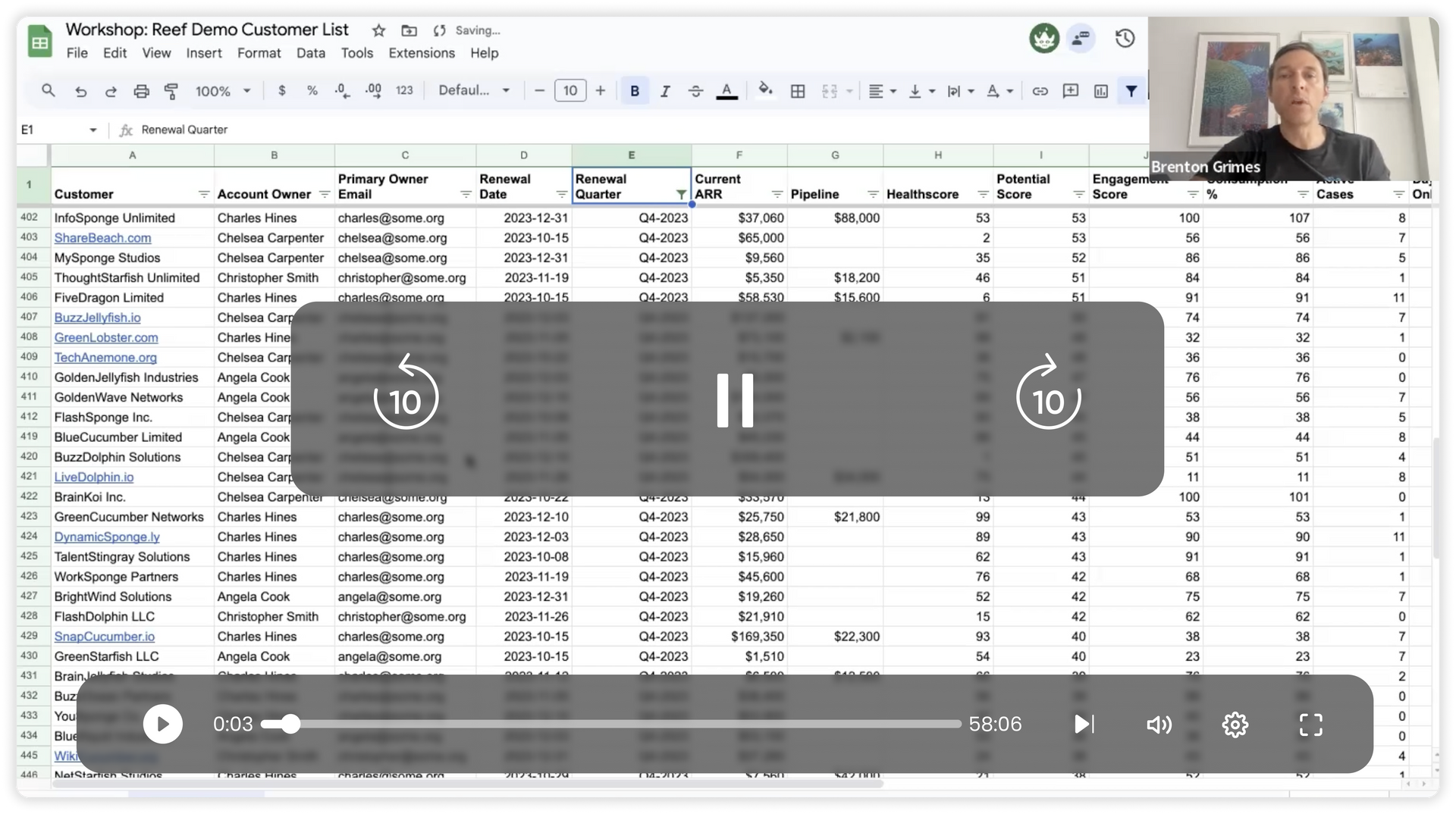 A man is sitting in front of a spreadsheet while playing a video.