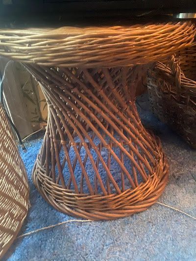 Wicker table with a round top and a twisted base, sitting on a blue surface.