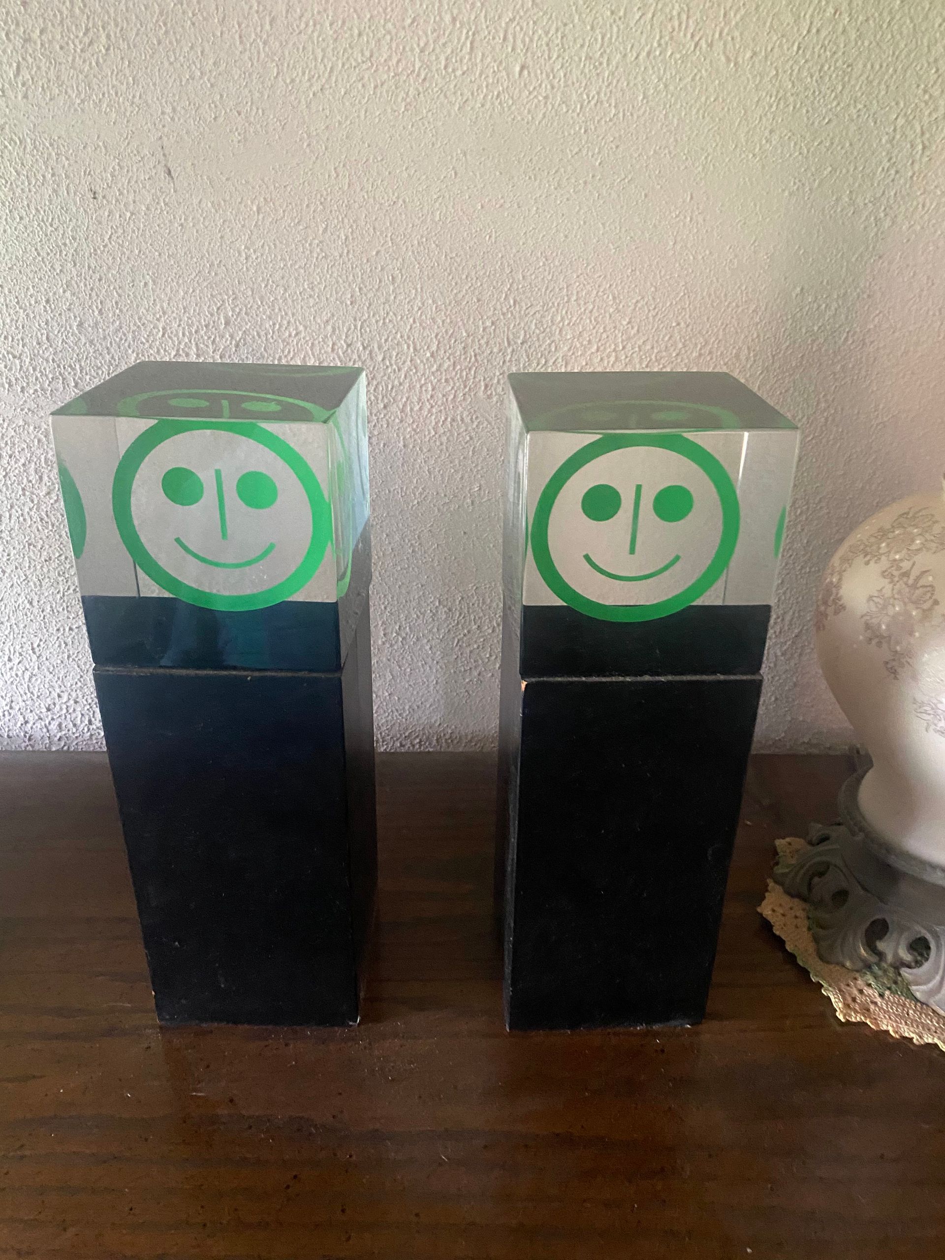 Two black rectangular objects with a green smiley face on top.