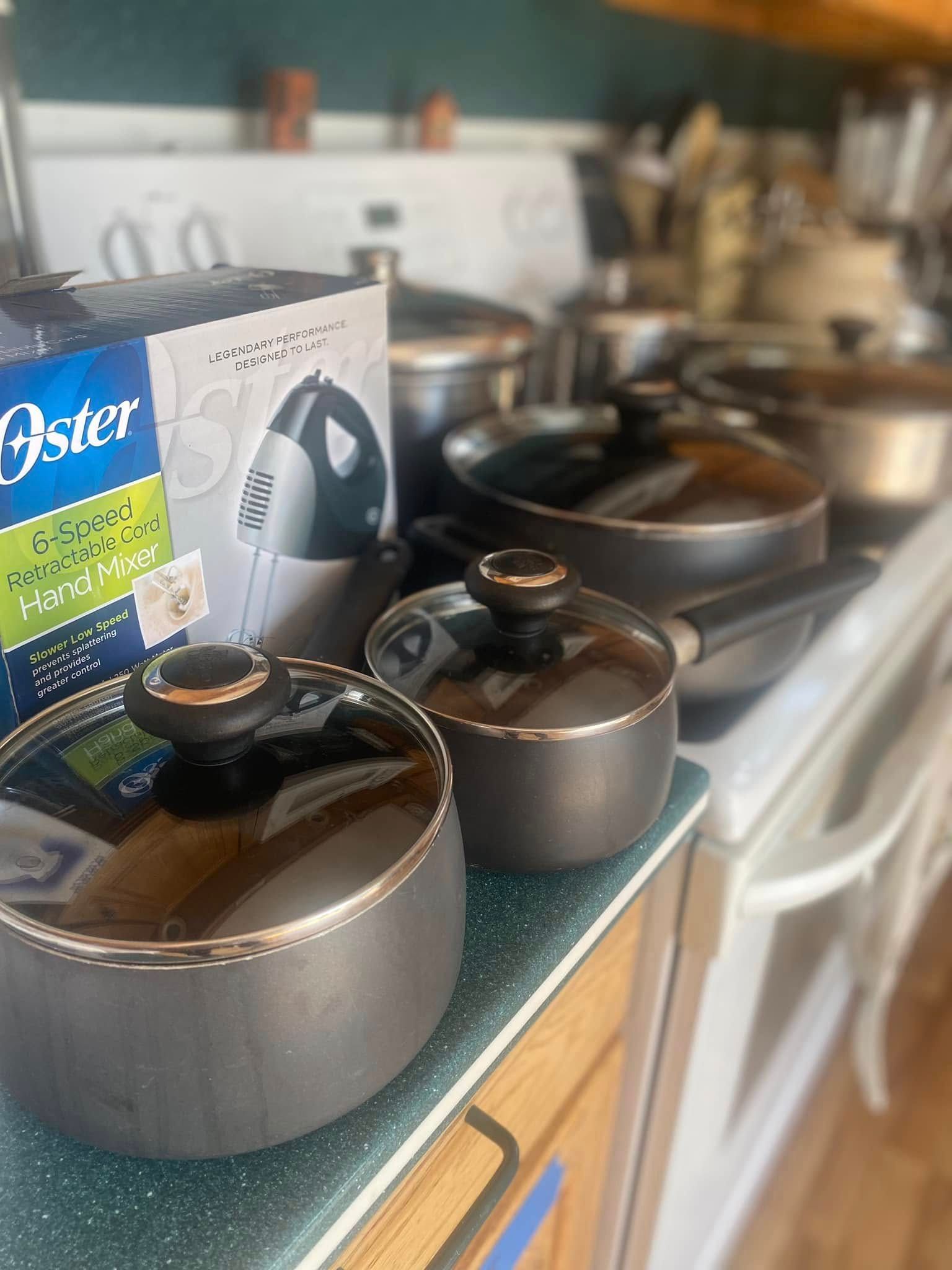 Pots and pans sit on a stovetop with an Oster blender box next to them.