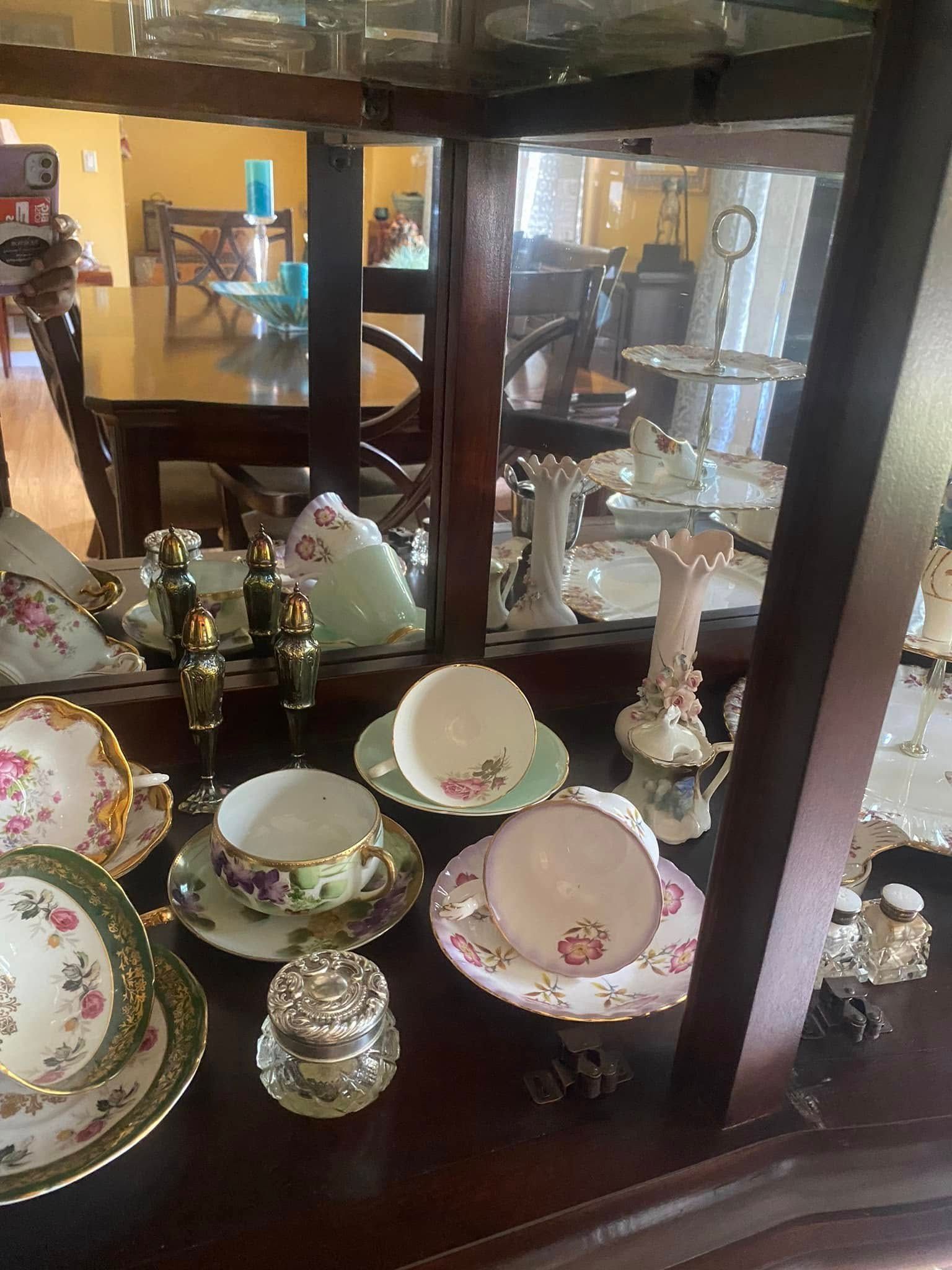 Display cabinet with teacups, saucers, and decorative items.