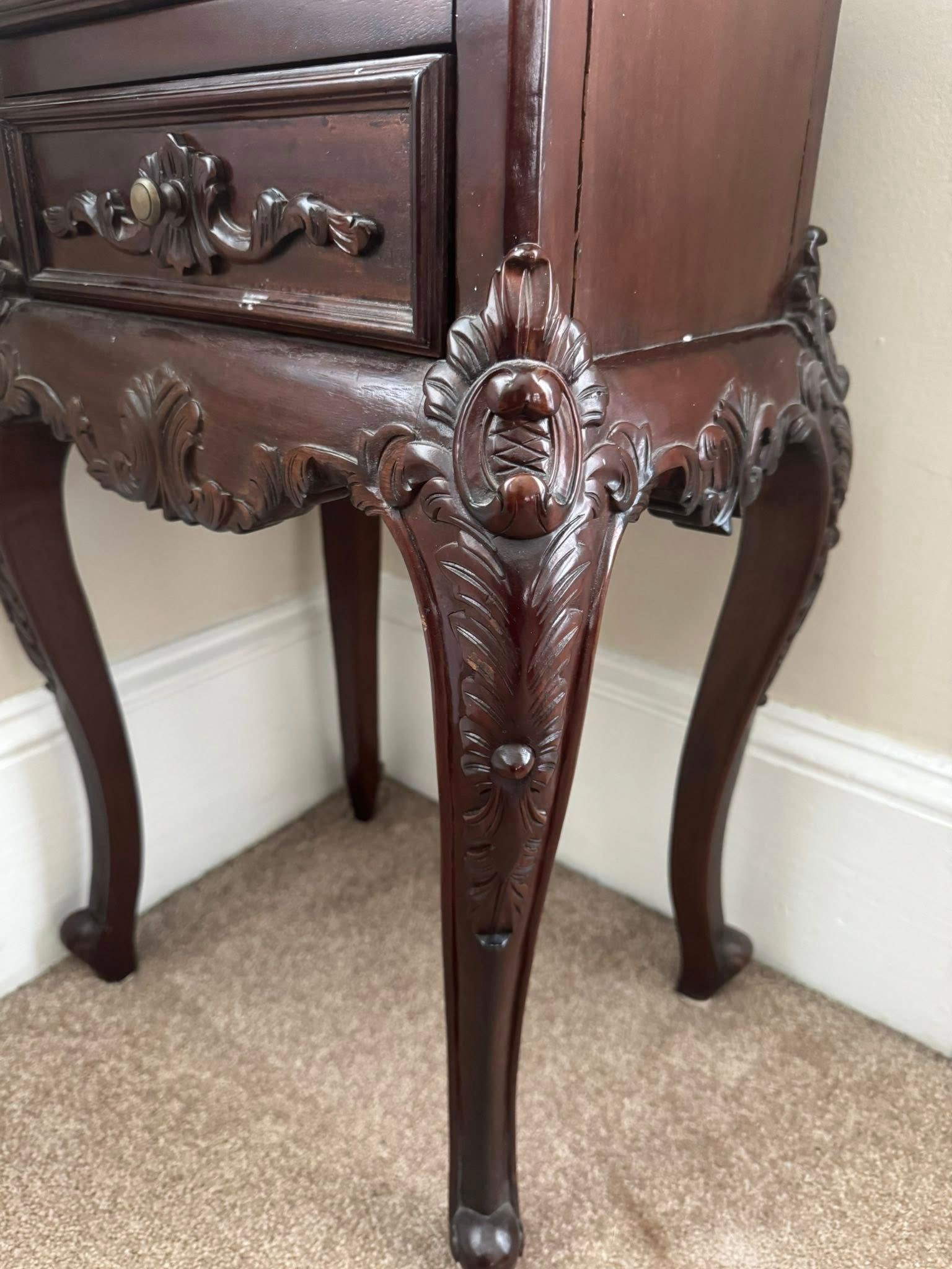 Dark wood nightstand with ornate carvings and curved legs.