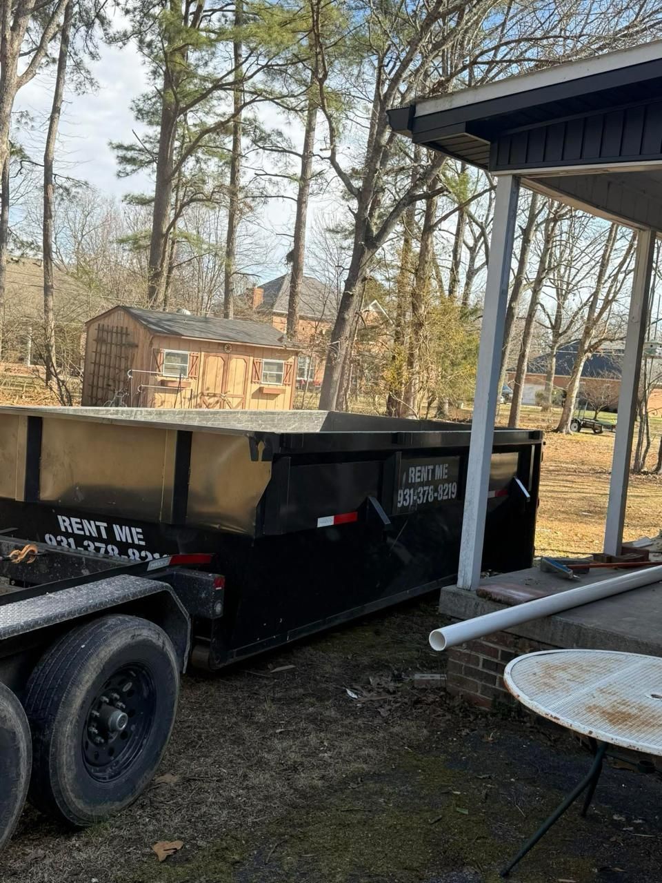 Family loading household items into Mid-Tenn Dumpster residential rental for home cleanout project