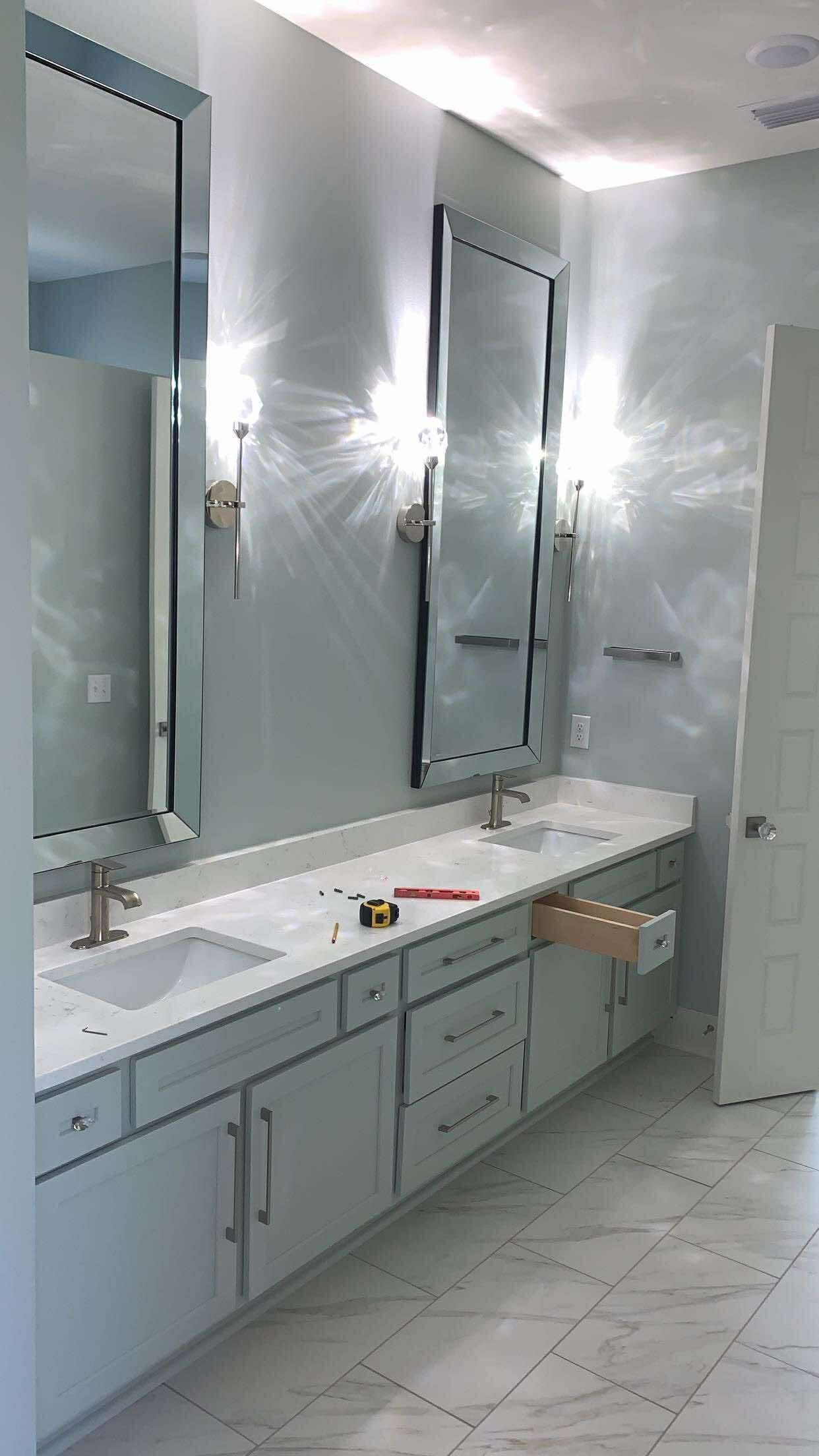 A long, light blue bathroom vanity with two sinks and mirrors, under bright lights.