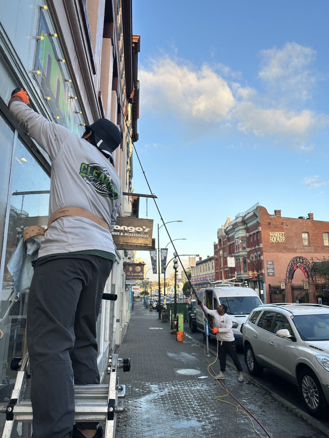 Professional window washer on ladder cleaning commercial window