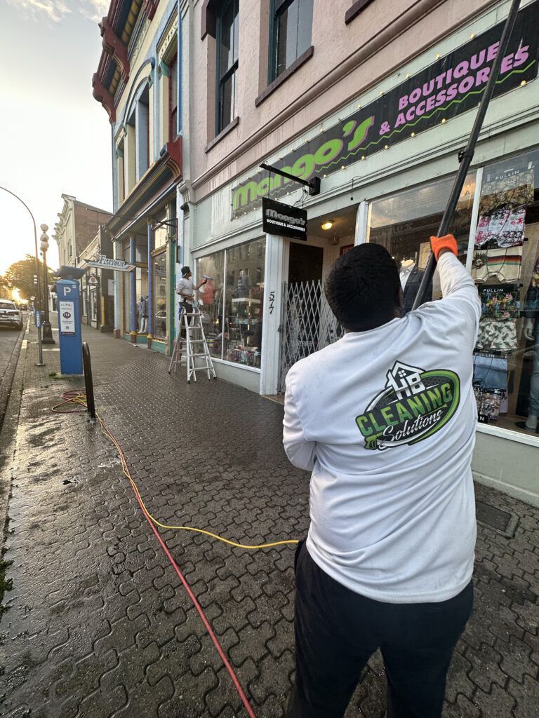 Professional window washer cleaning commercial windows in downtown Victoria, BC