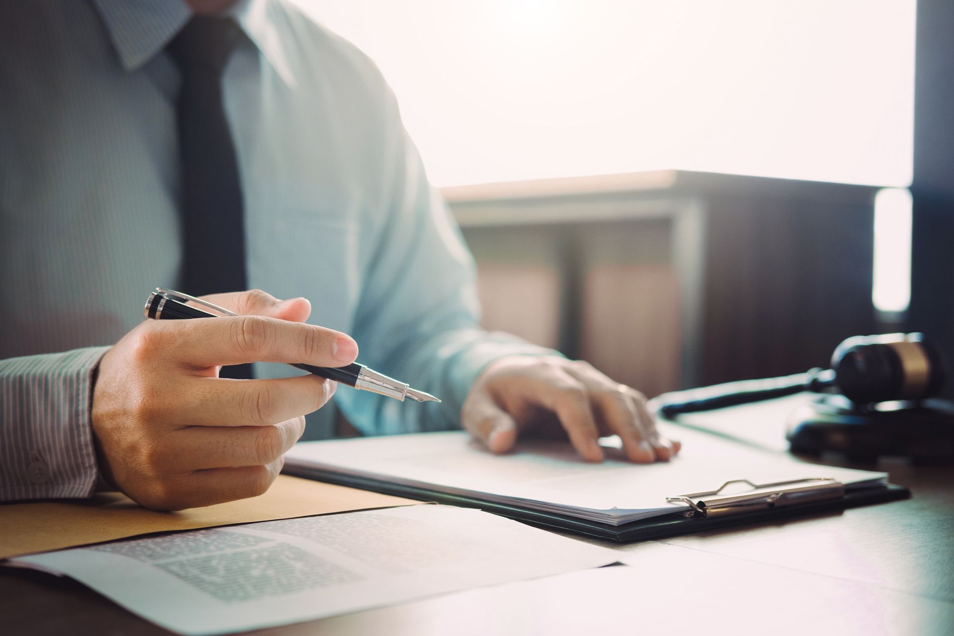 A lawyer is sitting at a table with a client and holding a scale of justice.