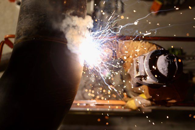 Construction worker welding metal beams, showcasing precise craftsmanship at a Colorado site.