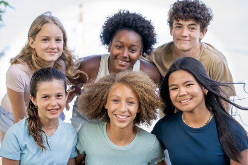 Group of smiling young people posing outdoors.