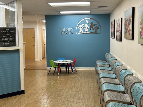 Waiting room with blue walls, colorful chairs, and artwork.