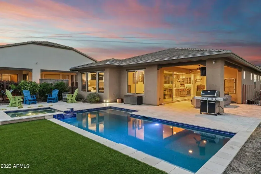 Desert home exterior with covered porch, wooden posts, and sunset sky.