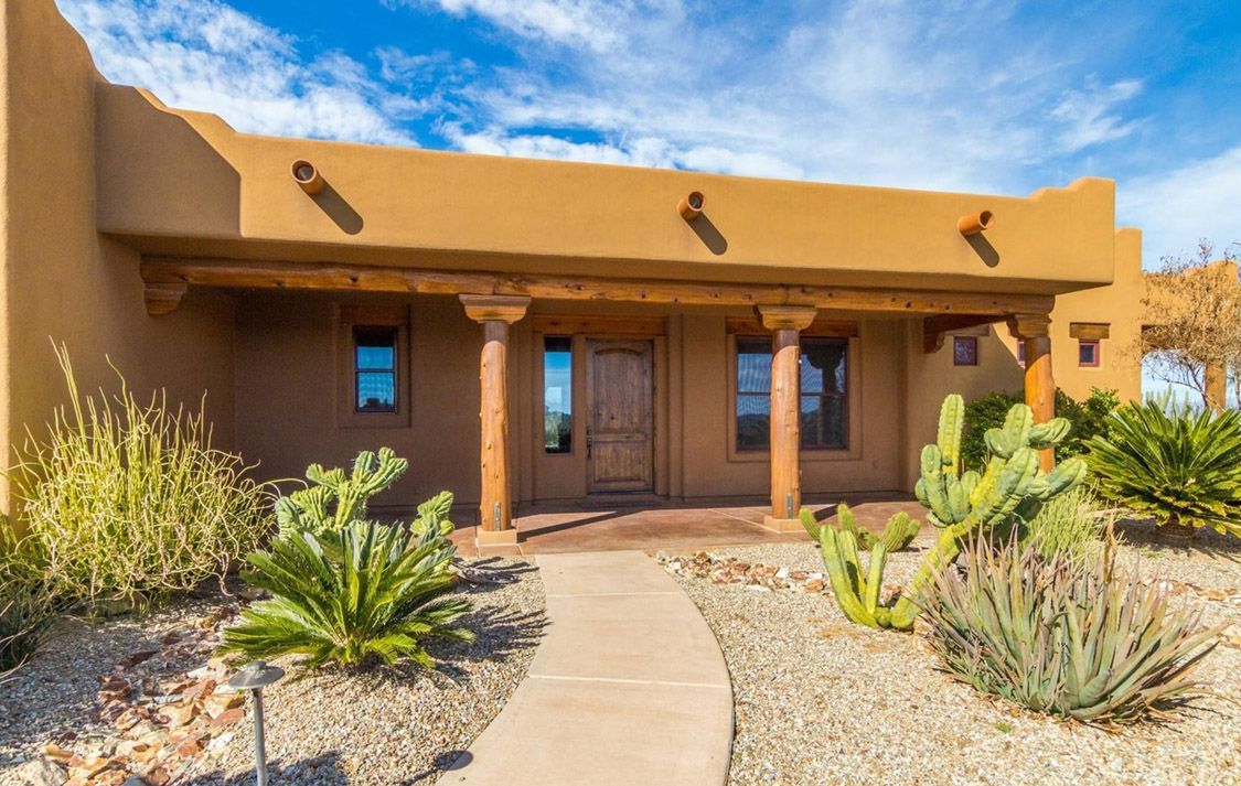 Southwestern style home with tan stucco, wooden columns, and desert landscaping.