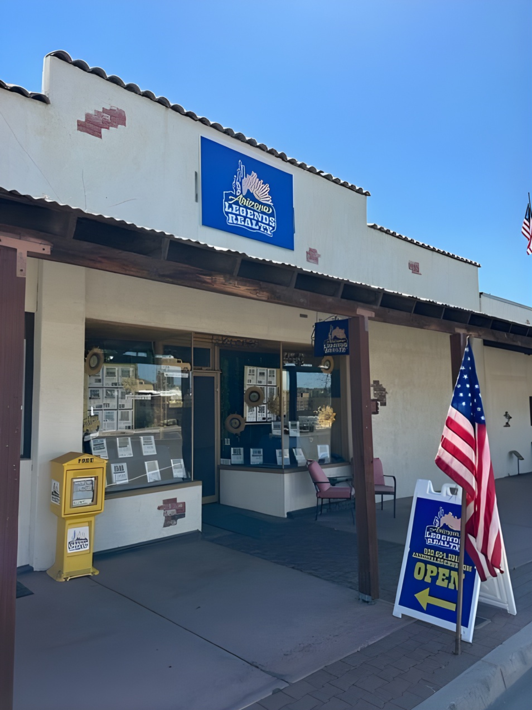 Storefront with a blue sign, American flag, and open sign.