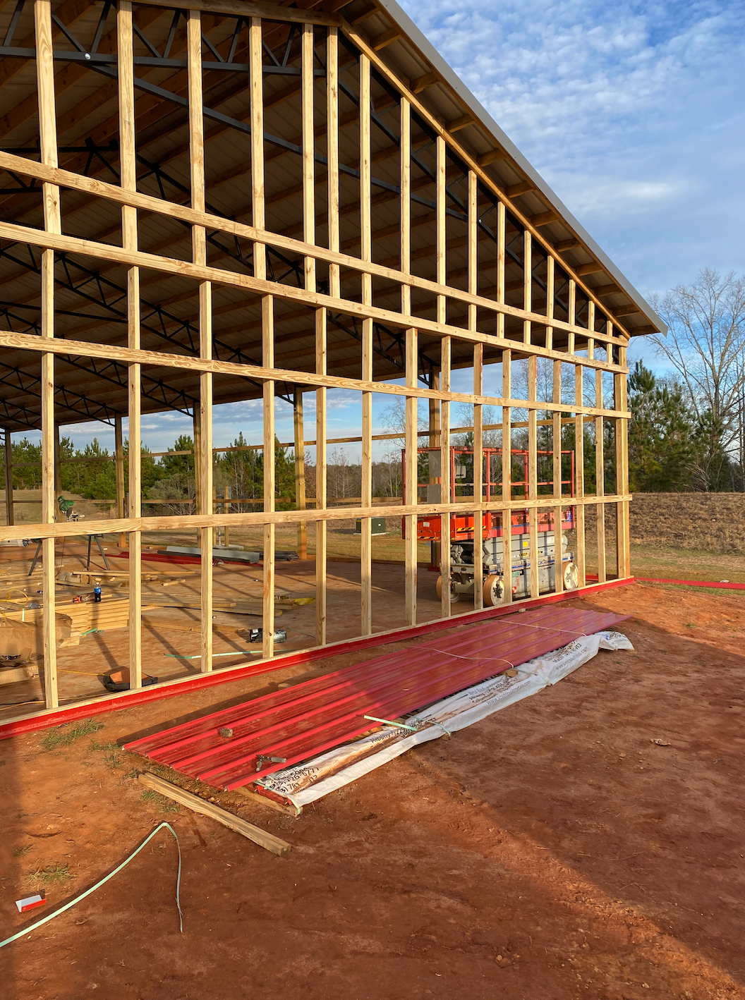 A large wooden building is being built in a dirt field.