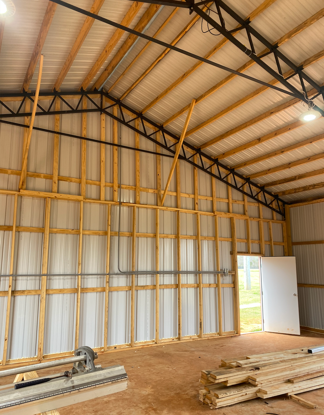 The inside of a building with a metal roof and wooden beams