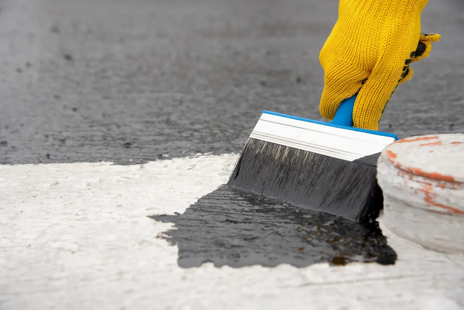 A person is painting a concrete surface with a brush.