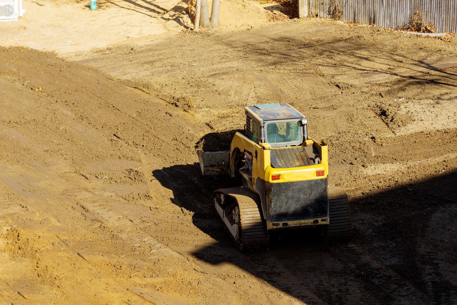 A yellow bulldozer is driving down a dirt road