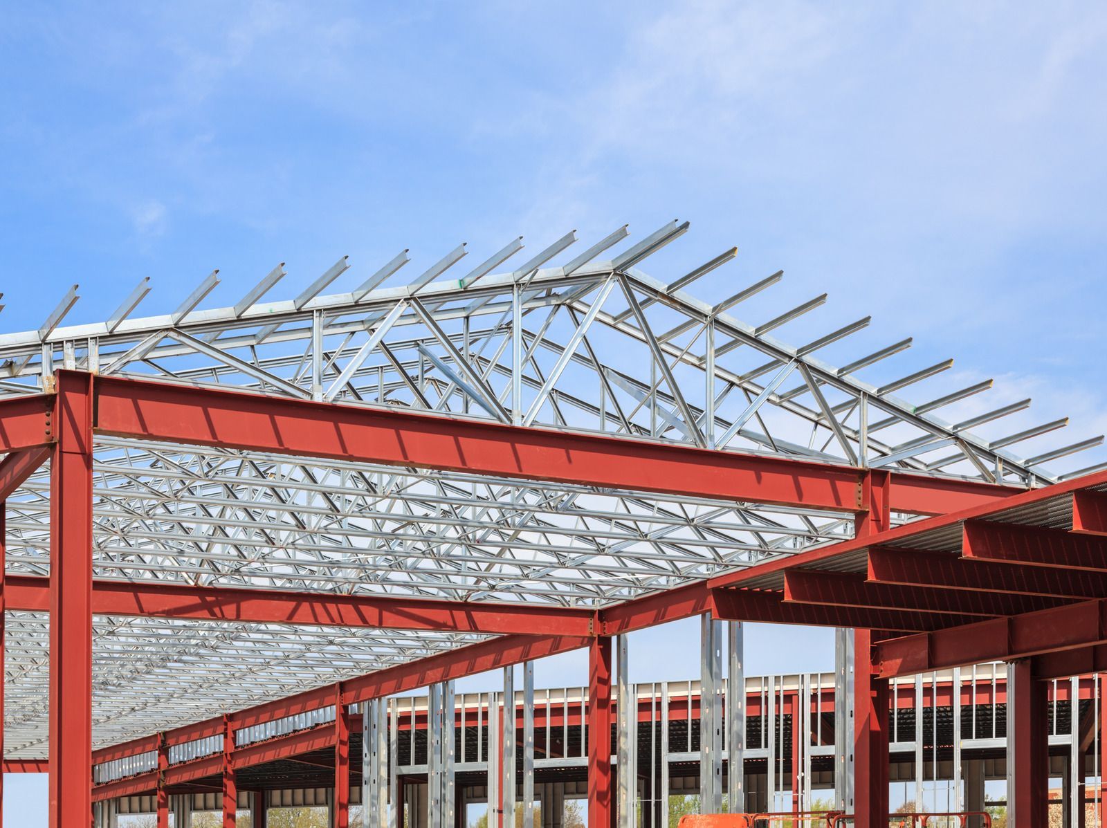A large metal structure is being built with a blue sky in the background.