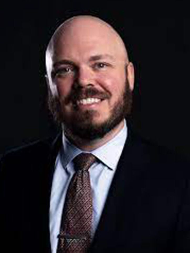Bald man in a suit smiles, posing for a professional portrait.