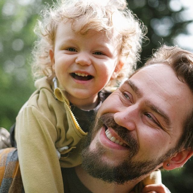 A man is carrying a little girl on his shoulders.