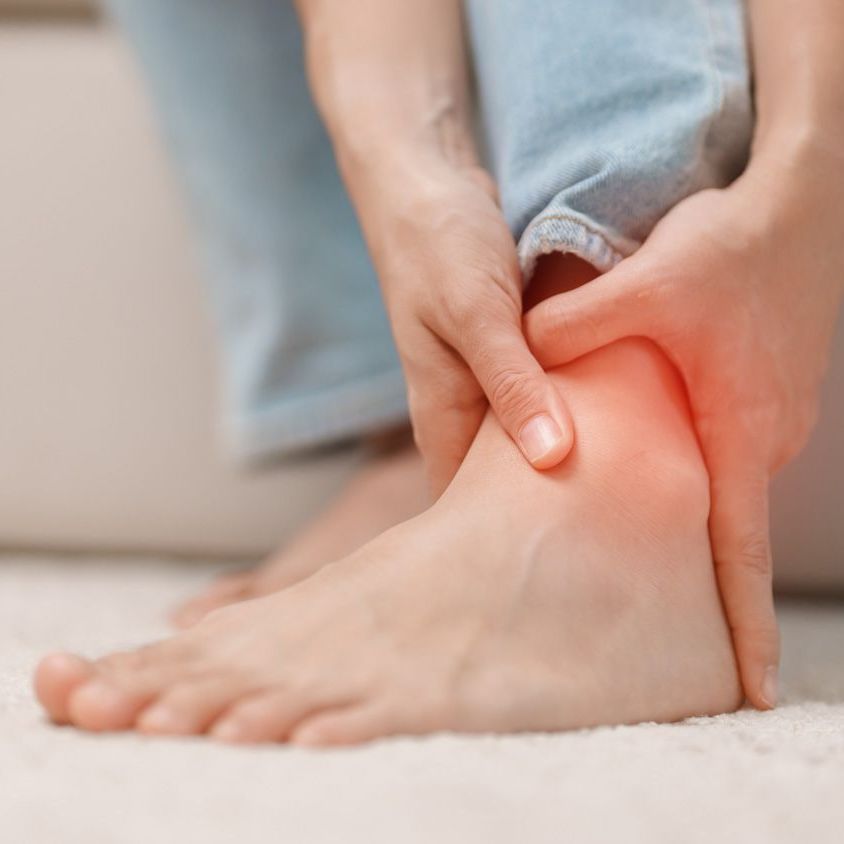 A person is holding their ankle in pain while running.