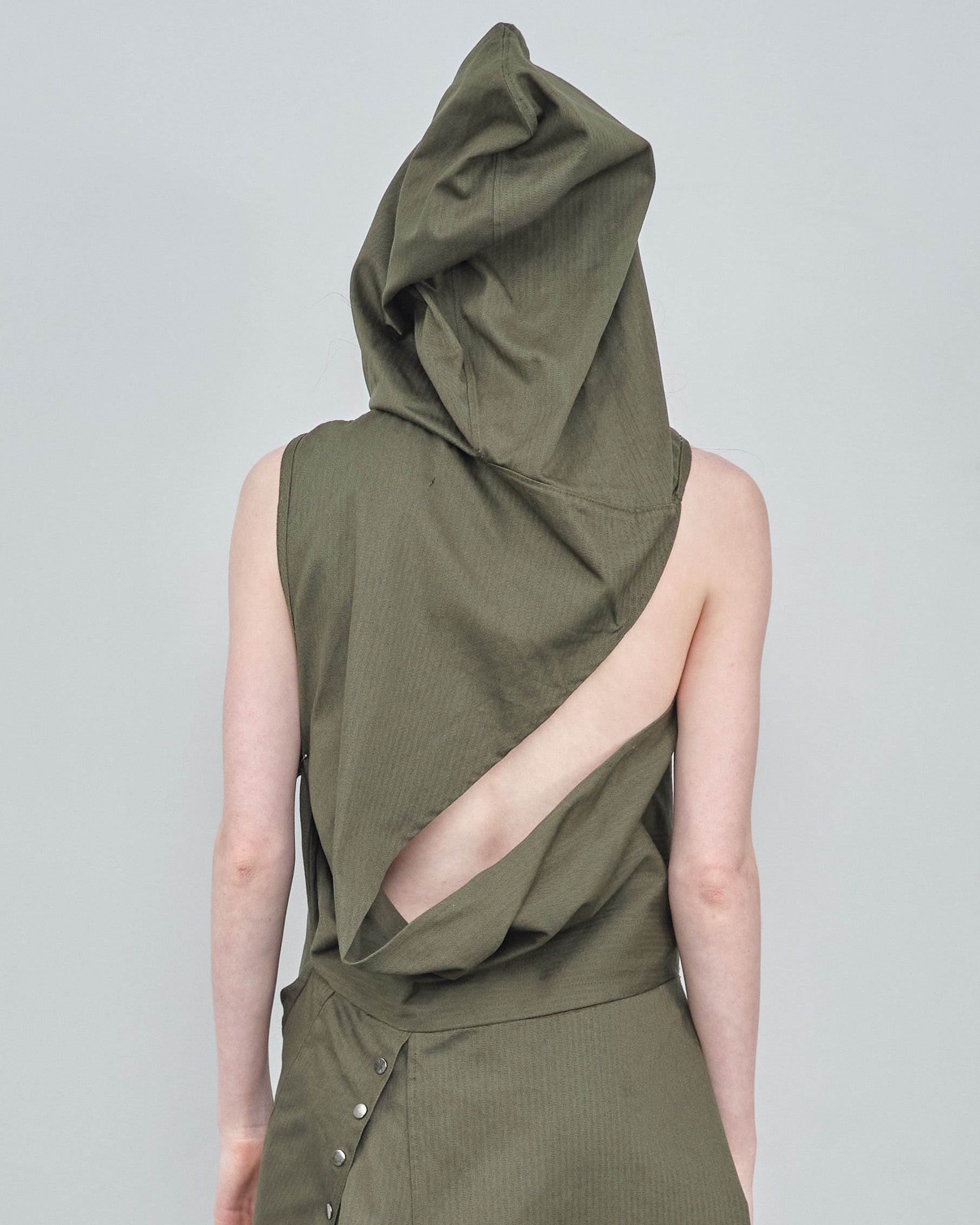 A woman wearing a green sleeveless top with a hood