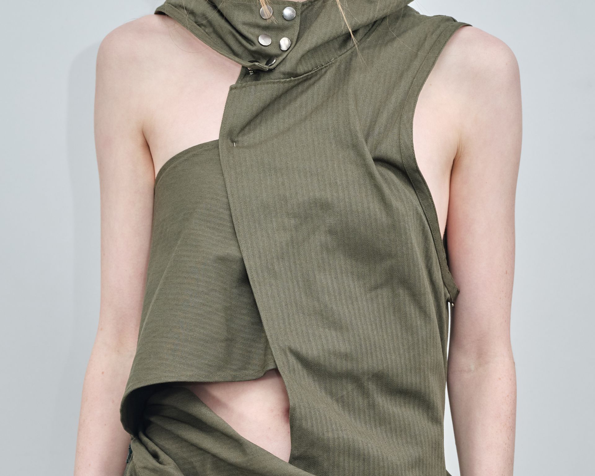 A woman is wearing a green top with a hood