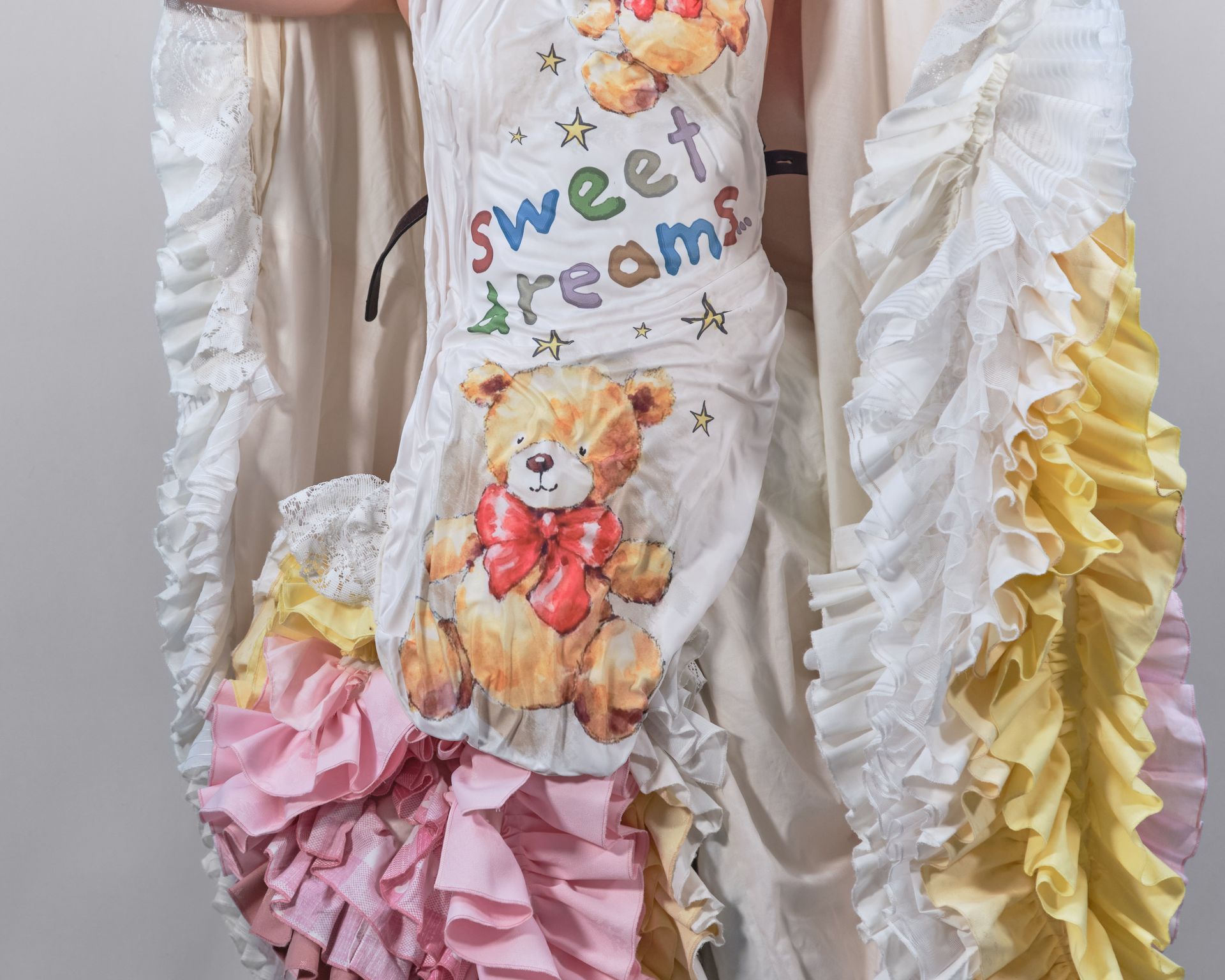 A woman is wearing a dress with ruffles and a teddy bear on it.