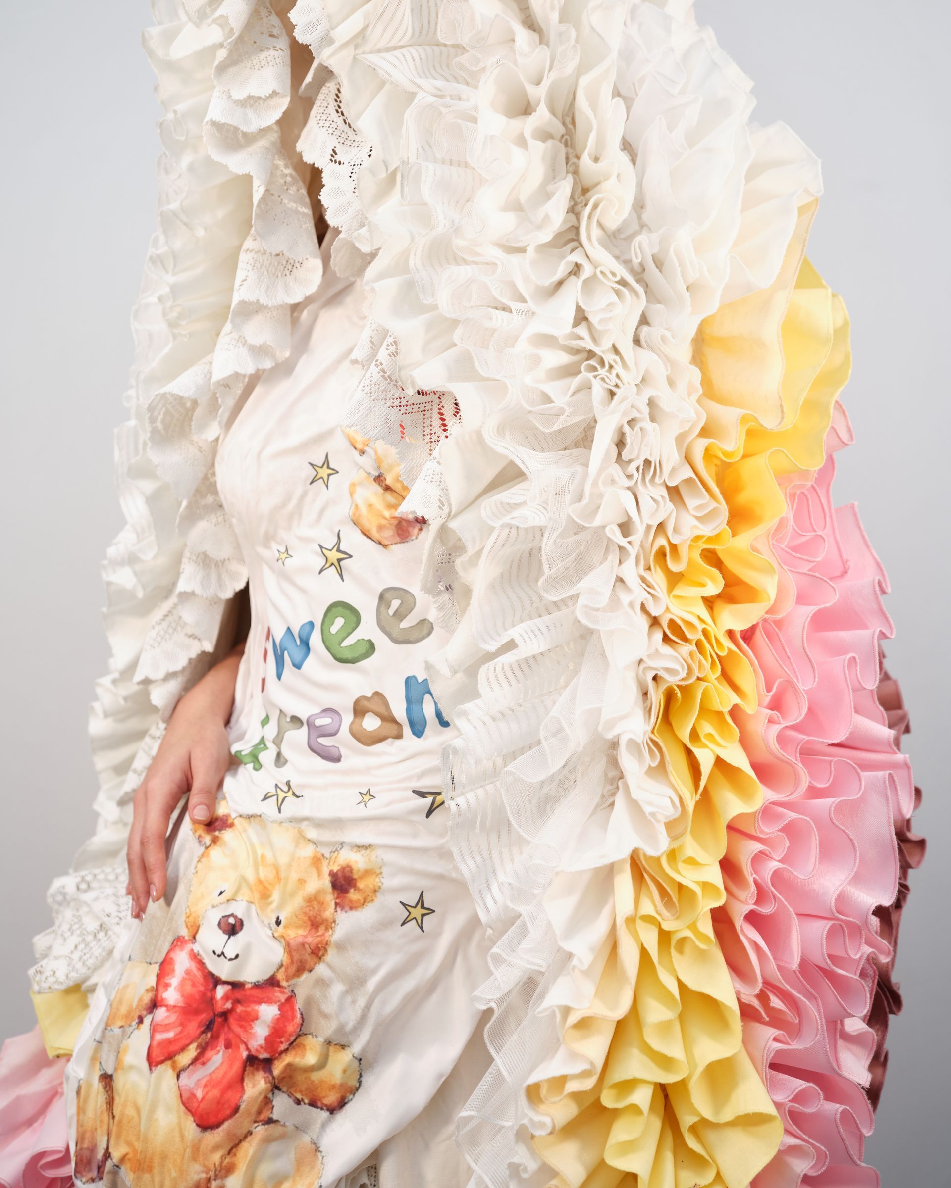A woman is wearing a white dress with ruffles and a teddy bear on it.