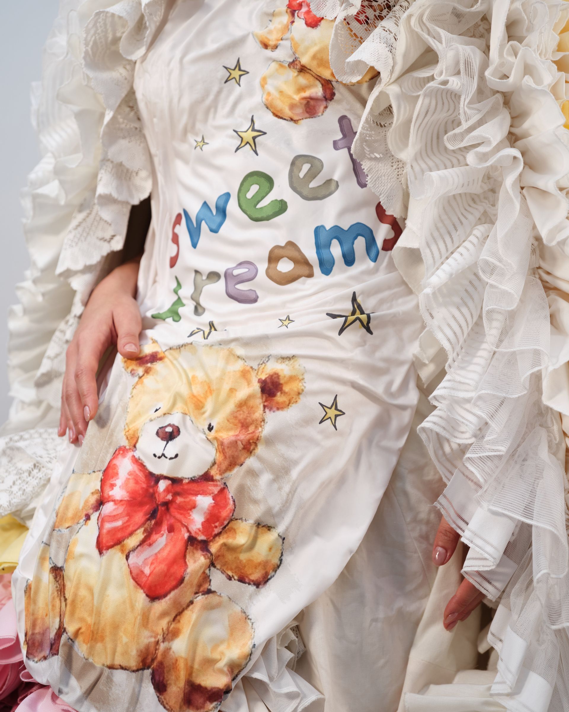 A woman is wearing a white dress with a teddy bear on it that says sweet dreams
